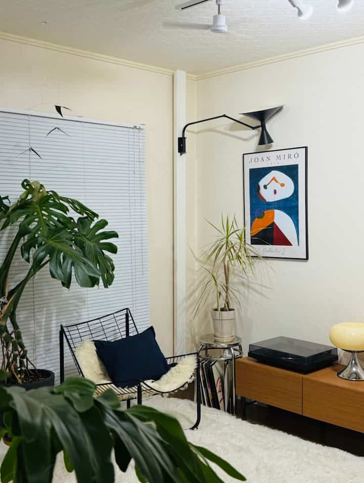 白と茶色の色調のリビングルーム、黒いアームチェアとサイドボードが配置されたナチュラルで落ち着いた雰囲気のインテリア