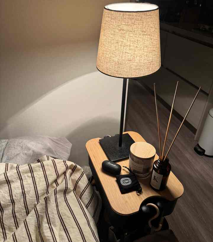 温かみのある木目調とナチュラルカラーの寝室、ナイトテーブルのテーブルランプが配置された雰囲気ある空間