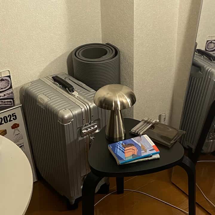 黒いサイドテーブルにシルバーの照明と本が置かれた一人暮らしのモダンなコーナースペース