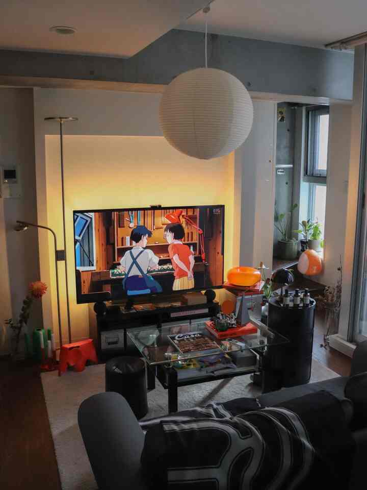 モノトーンとオレンジのアクセントが調和した北欧風リビング、二人掛けソファとペンダントライトが印象的な空間。