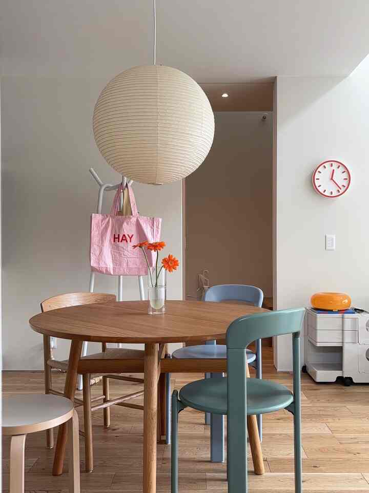 ナチュラルカラーのダイニングルーム、丸い木製テーブルと様々な椅子が配置された暖かく清潔感のある空間