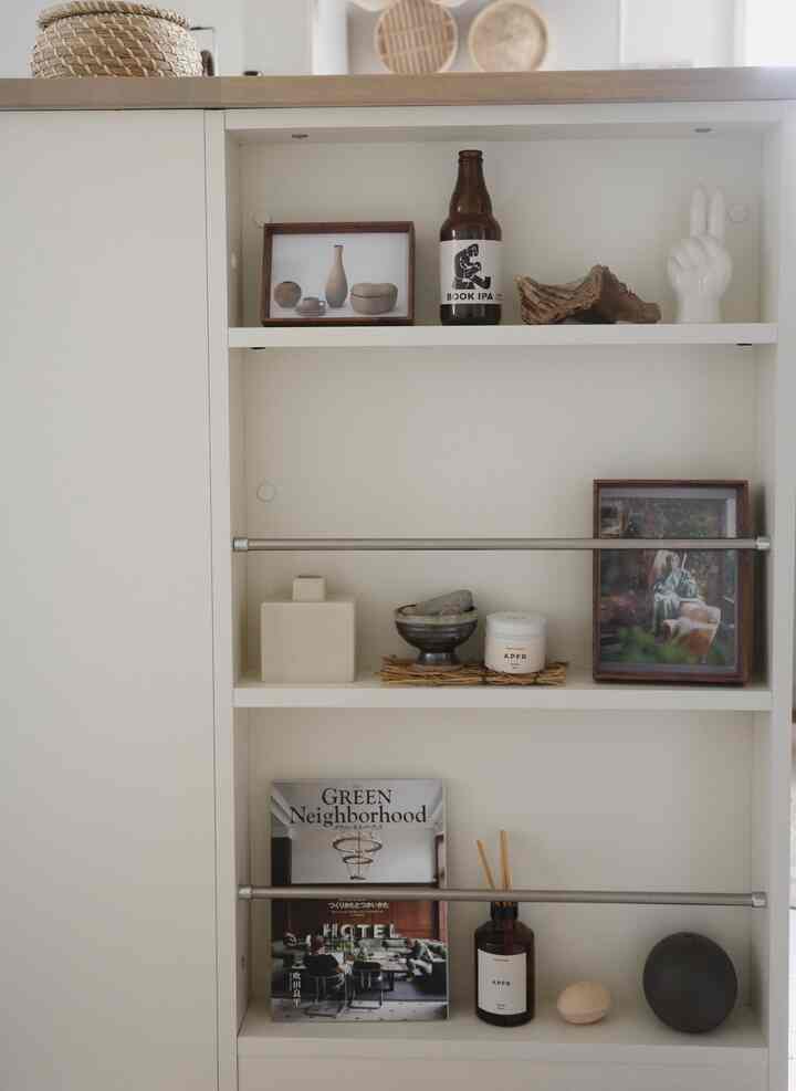 ナチュラルカラーのキッチン棚、アポテーケのディフューザーや多様なオブジェが配された雰囲気のあるミニマルなインテリア