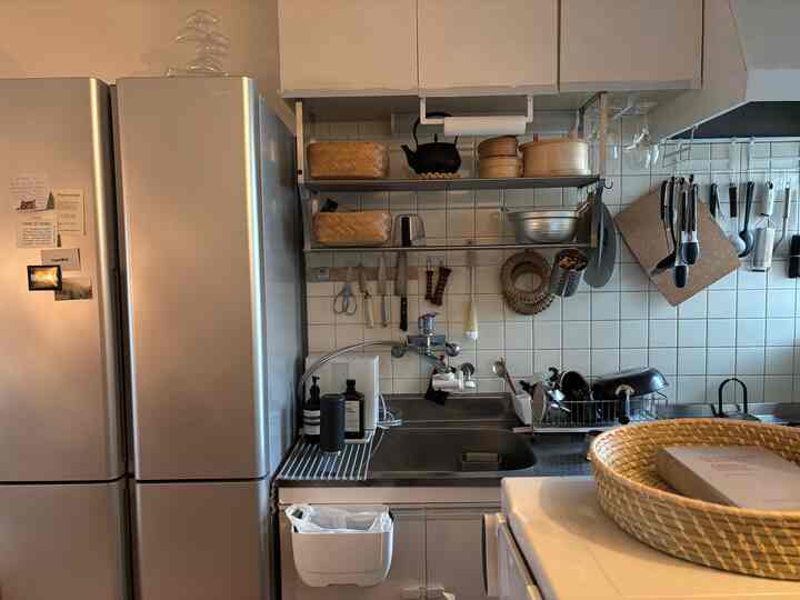 A cozy small kitchen in beige and gray tones featuring wall-mounted kitchen utensils and storage space