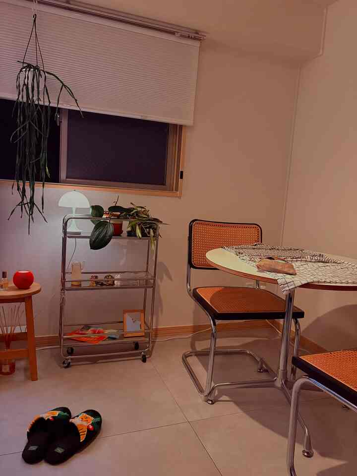 White-toned walls and soft lighting frame a cozy dining space with mid-century modern round table and chairs