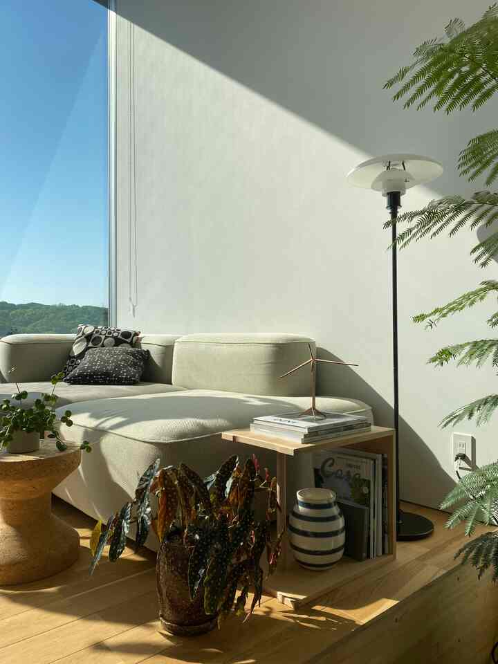 ベージュのソファと木目調の床、植物が配置された明るいリビングスペース