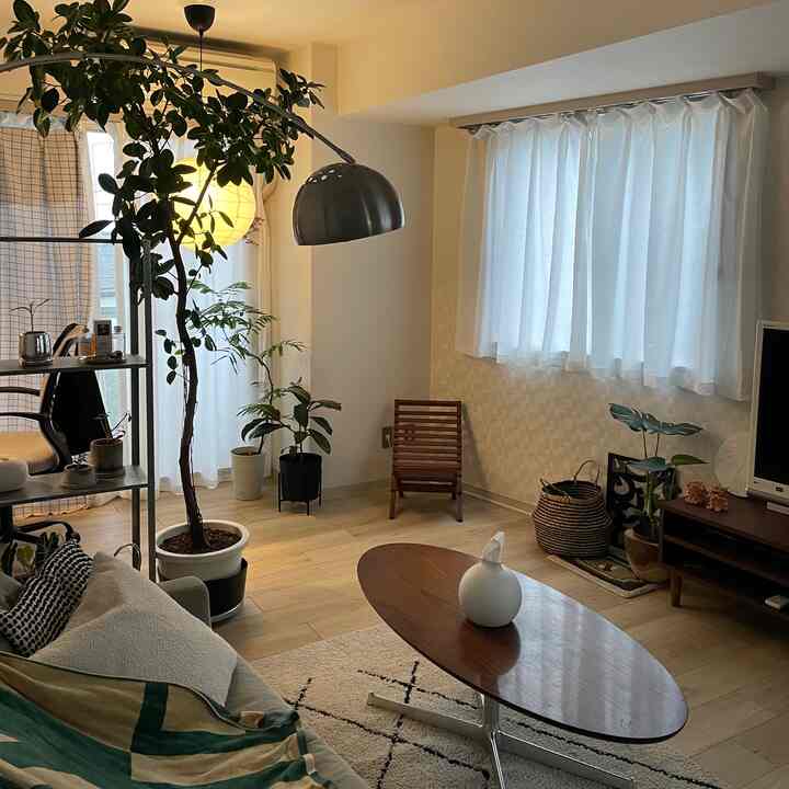 ナチュラルカラーのリビング、アーチ型のフロアランプとミッドセンチュリースタイルのコーヒーテーブルが配置された落ち着いた空間