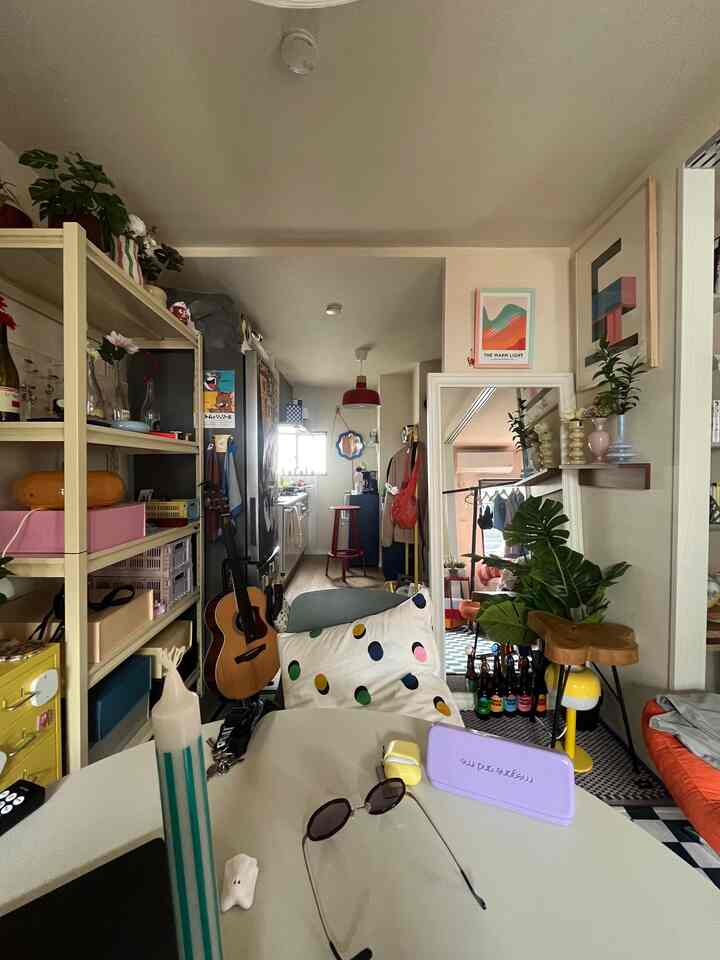 白と赤のトーンが特徴の縦長リビングとキッチン、植物や雑貨が配置された雰囲気のあるインテリア