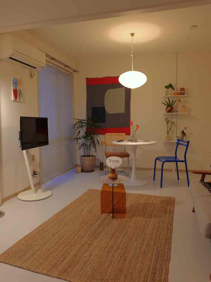 White-toned living and dining area featuring a rattan rug, round dining table, and varied dining chairs in a cozy modern space