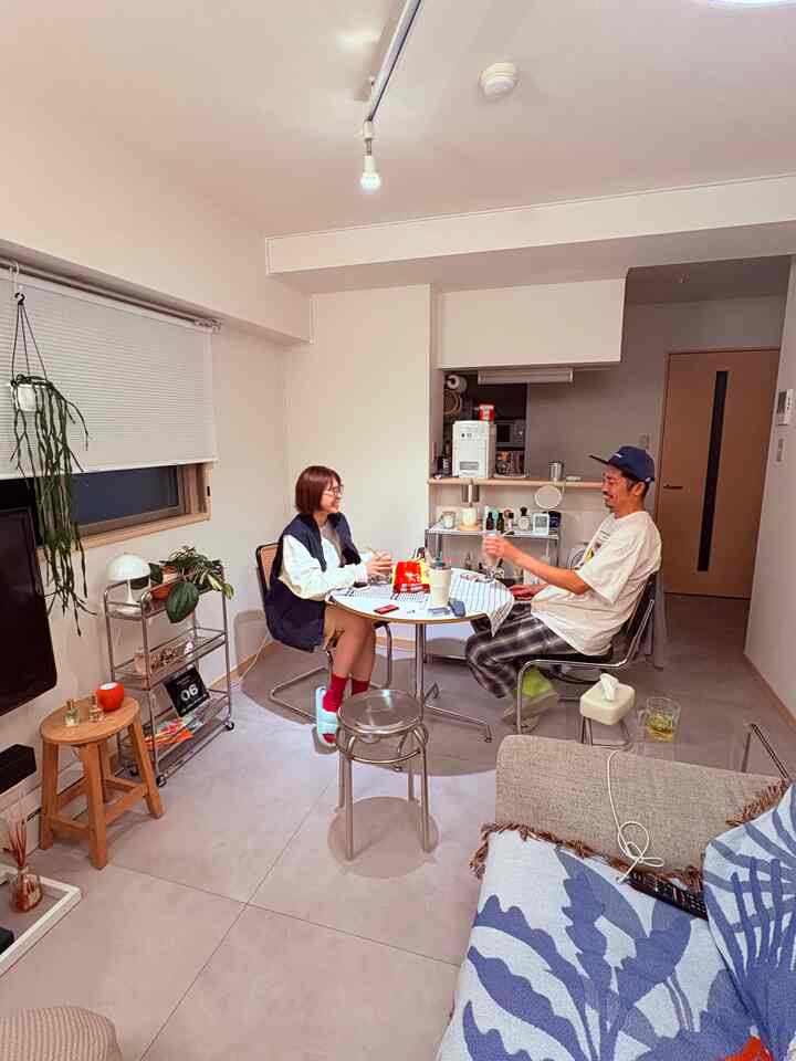 白を基調とした1LDKのリビング、丸テーブルとスツールが配置された雰囲気のあるホームパーティースペース