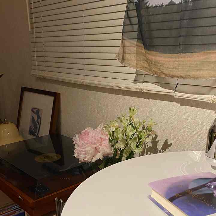 白を基調とした一人暮らしの空間、ブラインドやレコードプレーヤー、花瓶が配置された雰囲気のあるインテリア