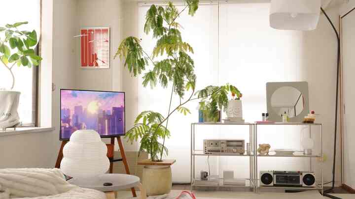 White and green toned living room featuring a floor lamp and large plants centrally and left positioned, creating a soft and gentle atmosphere