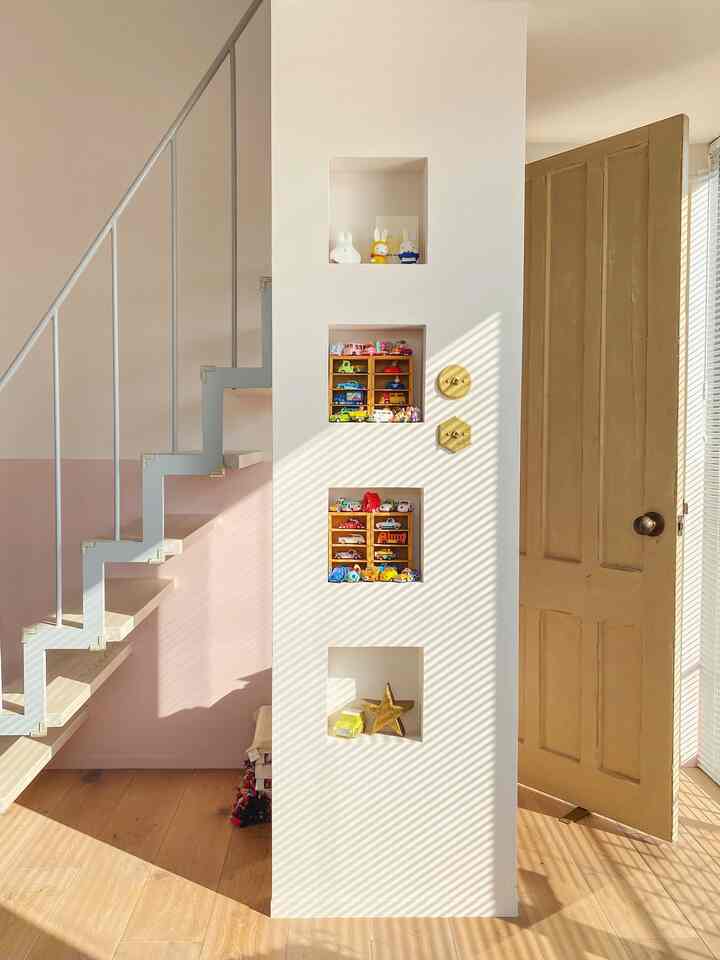 White and wood tone kids' room featuring stairs and built-in wall niches filled with toys, creating a cozy natural atmosphere