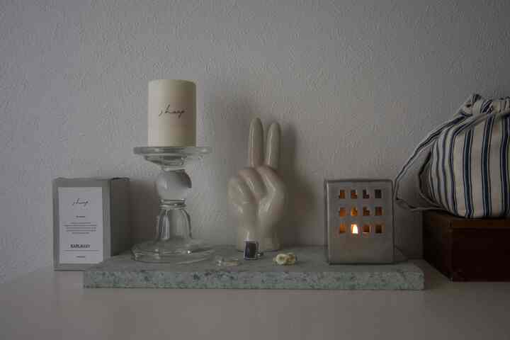 Natural-toned interior featuring a simple table adorned with a candle holder and a peace hand-shaped objet for decoration