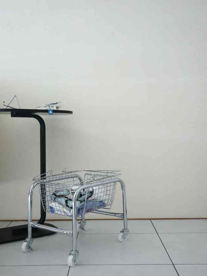 Simple interior space in white and metallic tones, featuring a metal basket and side table creating a minimalist atmosphere