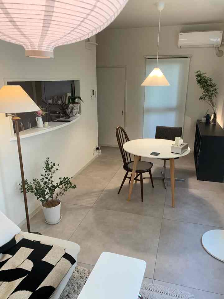 A compact and simple living dining space for two-person household in white and gray tones, featuring natural elements and plants for a cozy atmosphere