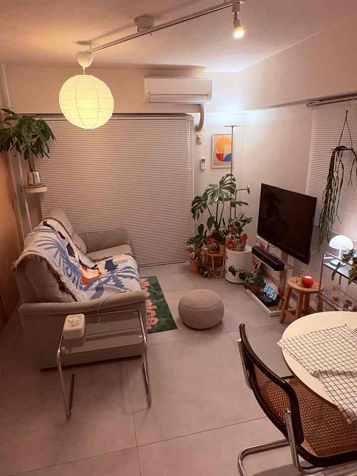 白い壁と天井のミッドセンチュリーモダン風リビング、中央に電動リクライニングソファと丸テーブル、右隅に植物が置かれた雰囲気のある空間