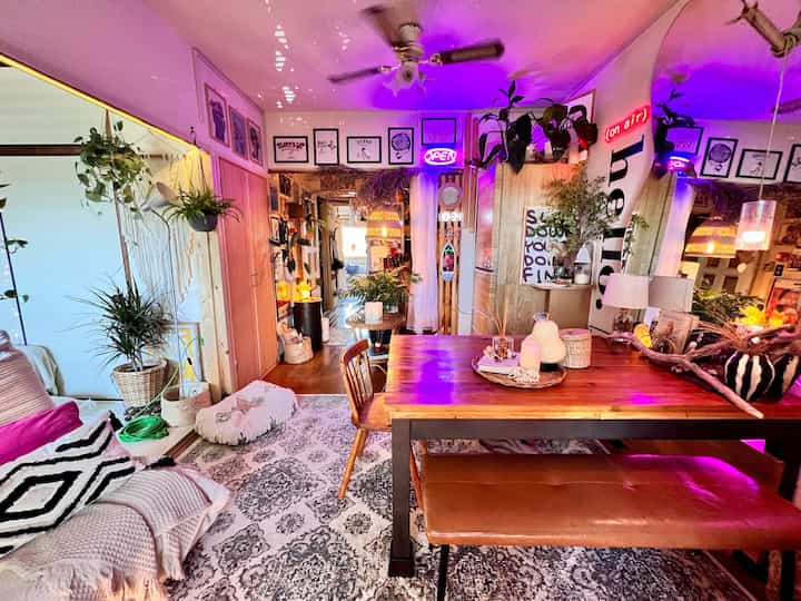 ウッドトーンとダークブラウンが支配的なネオンサインと細やかな装飾があるダイニングルームとキッチンスペース