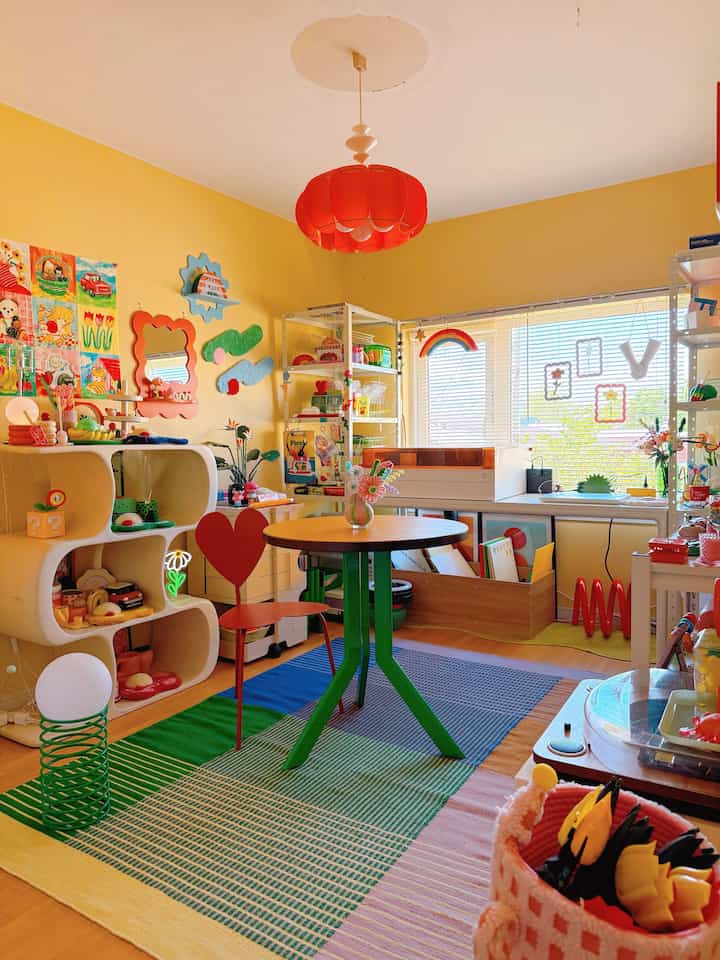 Bright yellow-walled colorful mid-century modern home office space featuring a window desk and red pendant light