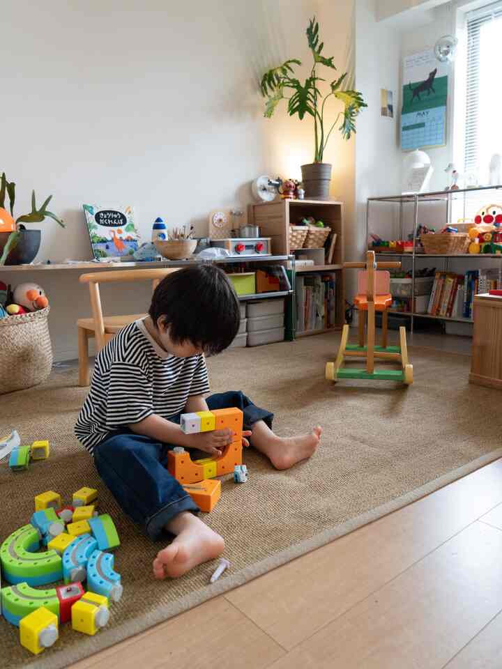 Natural-toned kids' room featuring a child playing with toys on the floor, creating a cozy atmosphere