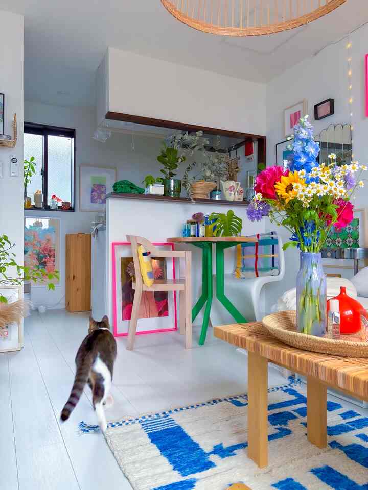 白を基調とした居心地の良いリビングとダイニング空間、猫や植物、多彩な花が配置された雰囲気あるインテリア