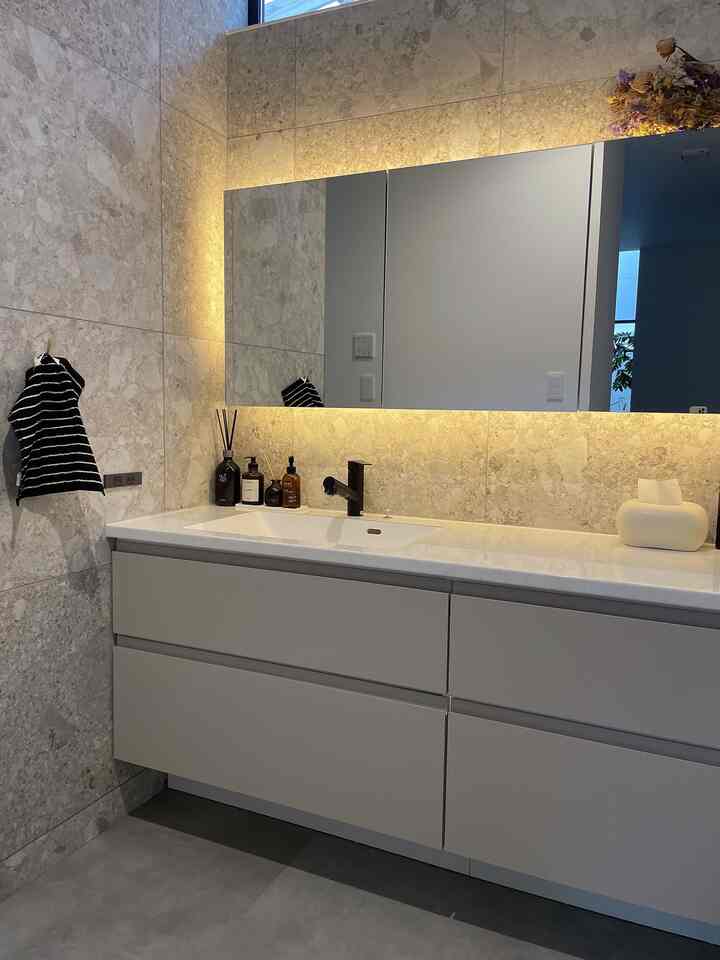 Gray stone-textured wall and white sink combine in a simple, natural bathroom space