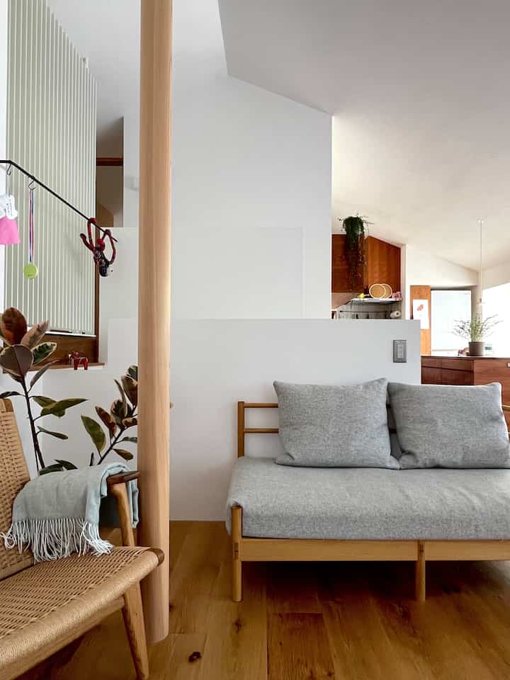 ナチュラルカラーのリビングとキッチンがゆるく繋がる空間、カールハンセン＆サンのアームチェアとシンプルなシーリングライトが配置された落ち着いたインテリア