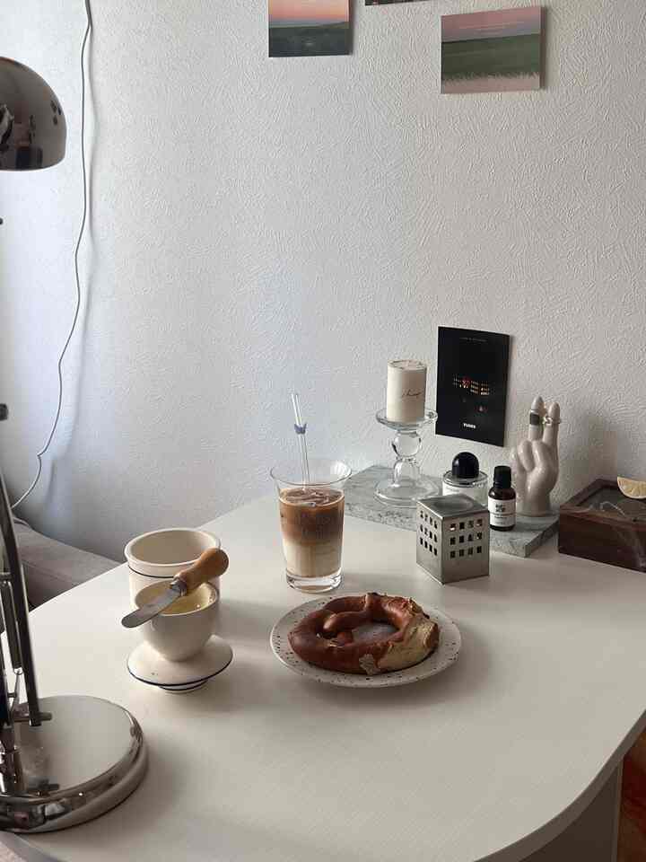 明るいホワイトトーンのダイニングルーム、テーブル上にはおうちカフェの飲み物とベーグルが置かれたシンプルでナチュラルなインテリア