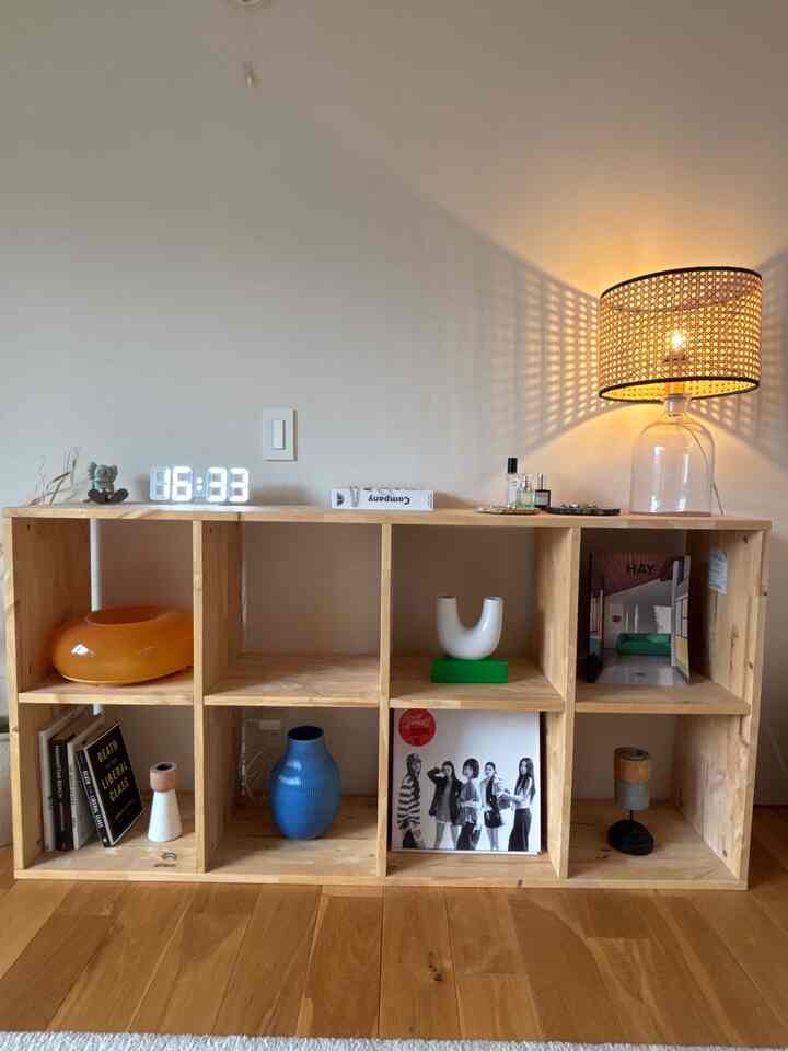 木目調の棚とラタン製テーブルランプが配置されたシンプルで北欧風のインテリア