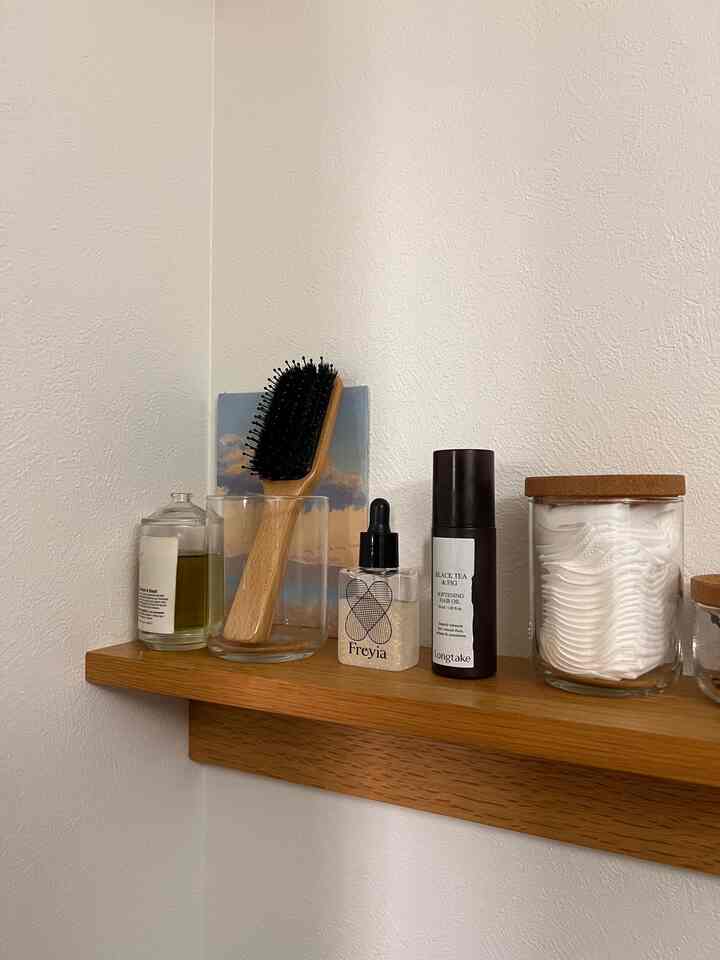 Natural color bathroom with white walls and wood tone shelf organized with bathroom essentials