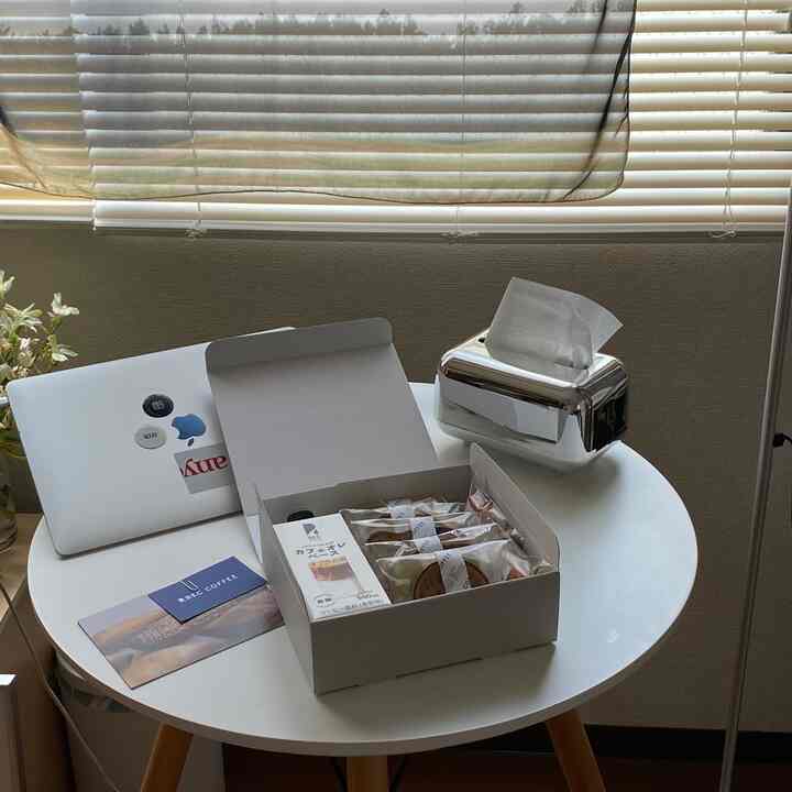 Cozy single household space featuring a white round table against blinds, with unsweetened cafe au lait and packaged pastries on top