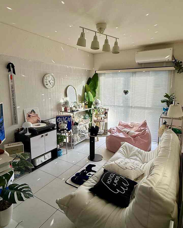 白とピンクの色調の6畳リビング、ソファとビーズクッション、サイドテーブルと植物が配置された雰囲気のある空間