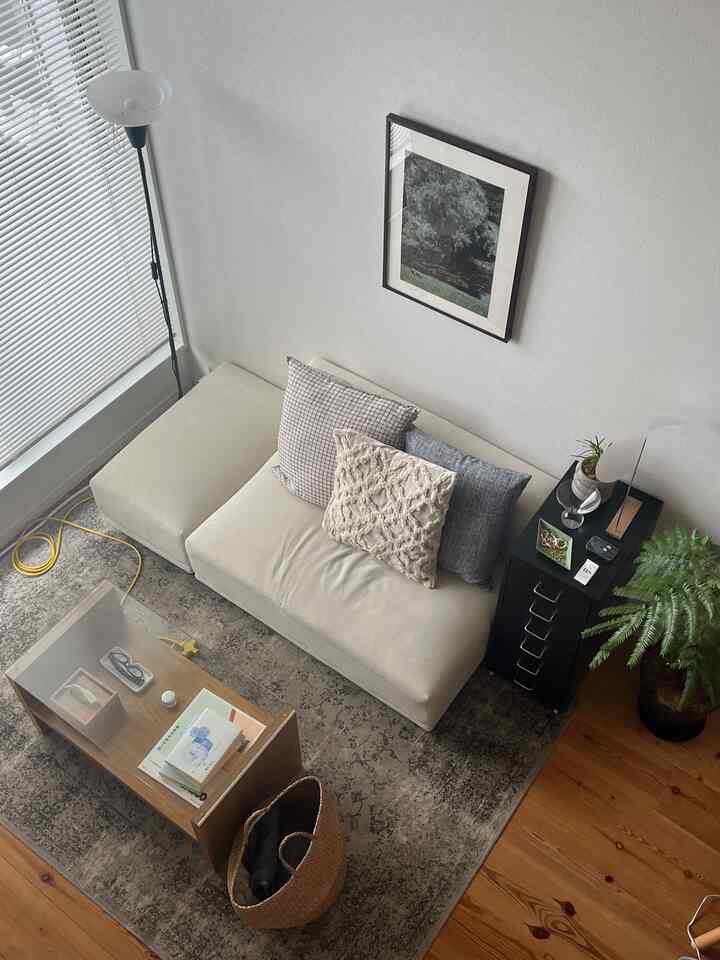 明るいベージュのソファとガラスのコーヒーテーブルが配置されたナチュラルウッド調のリビング、落ち着いた雰囲気のインテリア