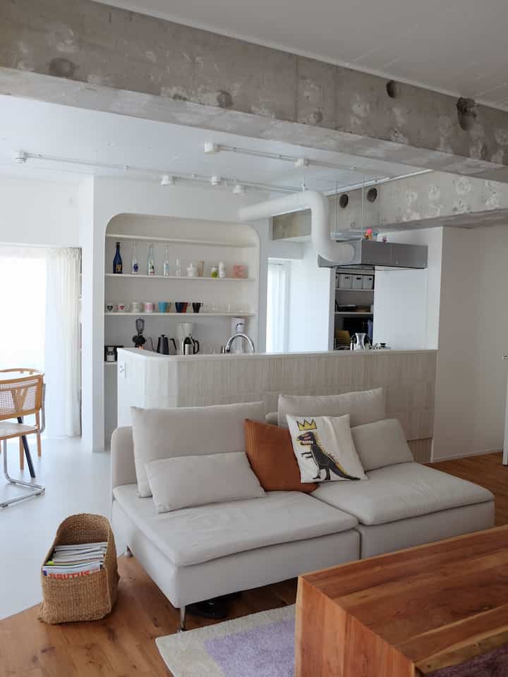 Beige and wood-toned natural living room and kitchen for two-person household featuring home cafe items neatly displayed