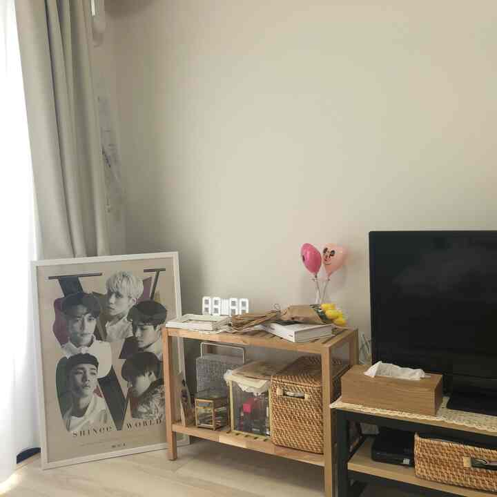 Calm white and natural wood-tone living room featuring wooden shelves and TV stand, showcasing minimalist Korean interior style