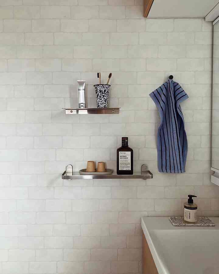 White-walled bathroom featuring stainless steel wall shelves and blue towel with a clean, simple atmosphere