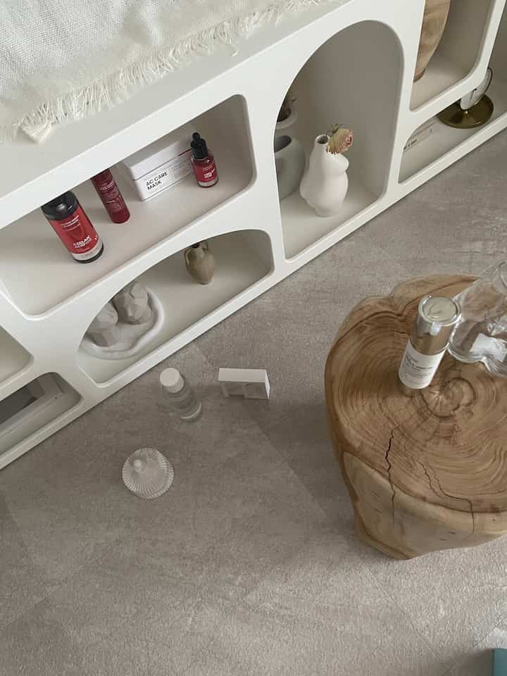 ナチュラルな木製スツールとグレーのフロアタイル、オブジェが配置されたシンプルモダンな韓国風リビングのインテリア