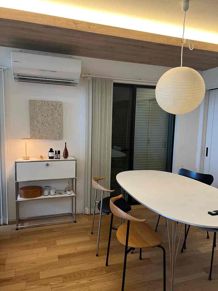 白と木目調が調和するミッドセンチュリーモダンのダイニング、丸いペンダントライトとシンプルなダイニングチェアが配置された落ち着いた空間