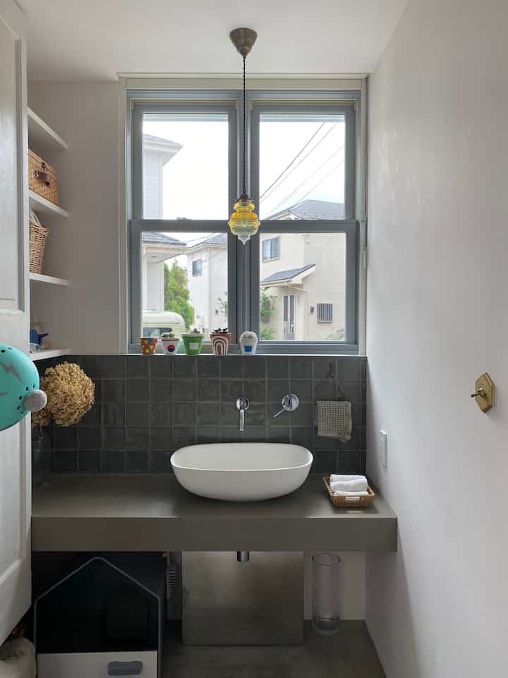 ナチュラルカラーとタイル壁が調和したバスルームの洗面台空間、自然光が明るく差し込む温かみのあるインテリア