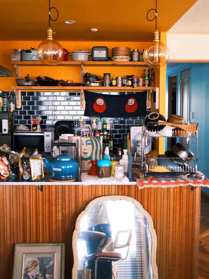 Yellow walls and ceiling dominate a natural kitchen space with wooden island and black tiles