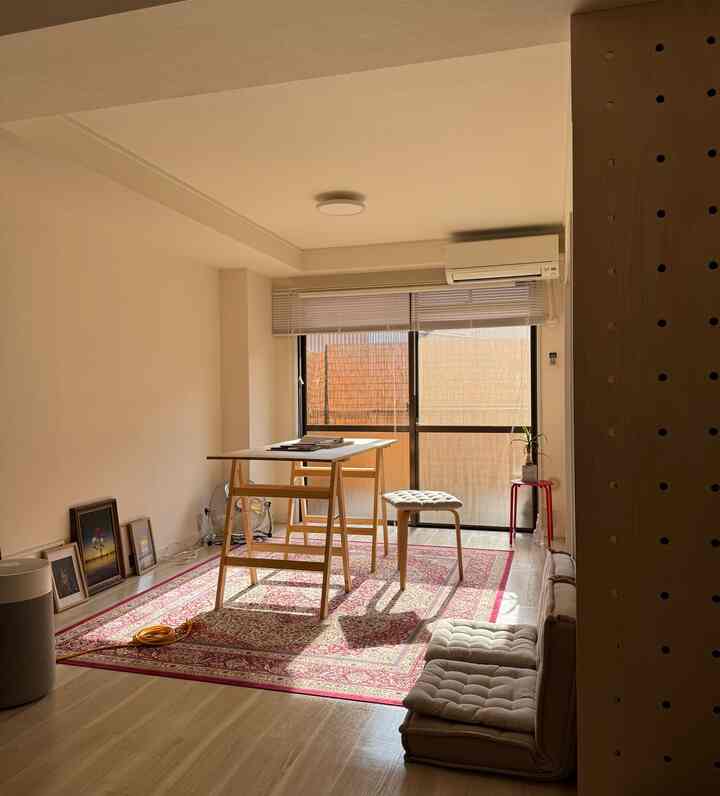 ナチュラルな色調のリビング、中心に木製の机とベージュのフロアクッションが配置された明るく落ち着いた空間