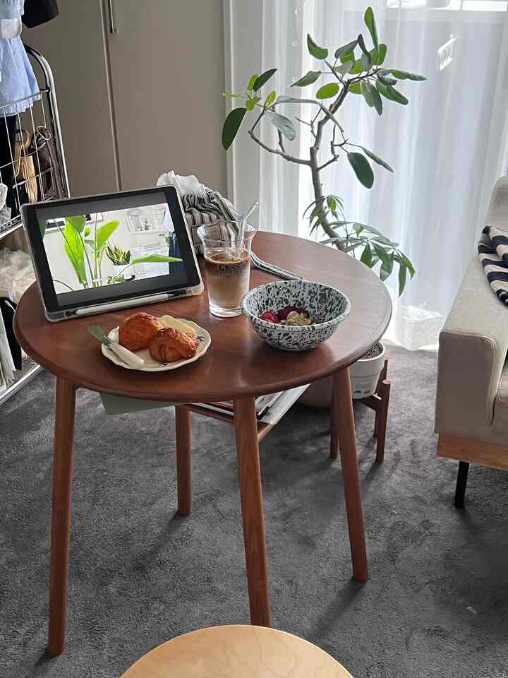 木目調とグレーのリビング、丸いダイニングテーブルにホームカフェのセッティングと食器が置かれた雰囲気のあるインテリア