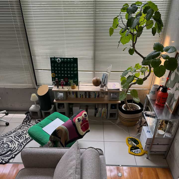 A calm-toned living room featuring a gray sofa, green plant, and IKEA shelf unit in a modern interior