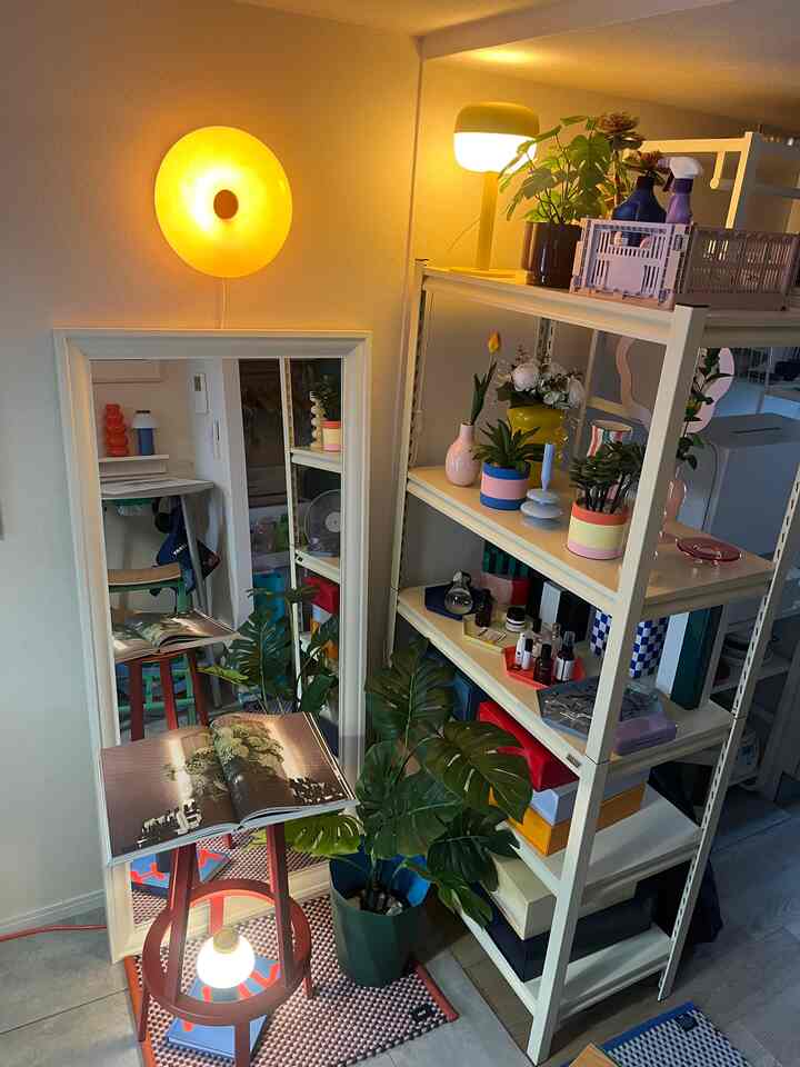 Cozy space featuring yellow lighting, white shelving, red stool, and green plants