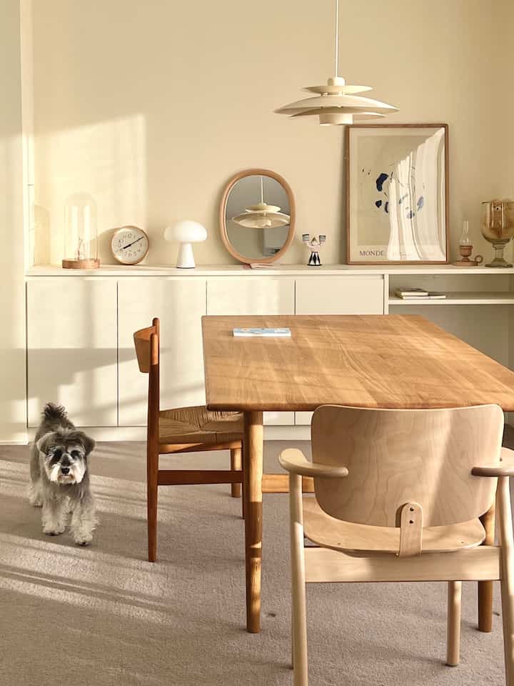 Natural wood tones and beige walls in a dining room featuring a wooden dining table and chairs centrally arranged, creating a cozy atmosphere