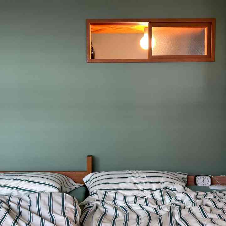 木目調と緑の壁が調和した二人用の寝室、シンプルでナチュラルな雰囲気のあるインテリア