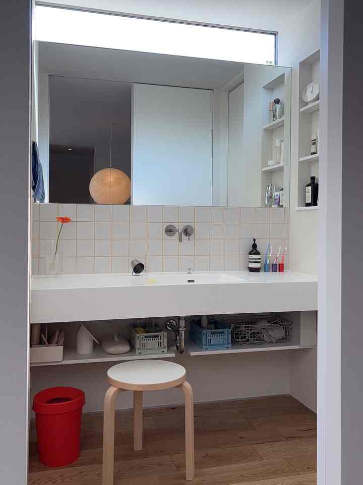 白とナチュラルウッドトーンのパウダールーム、すっきりとした洗面台と収納が配置された雰囲気のあるインテリア