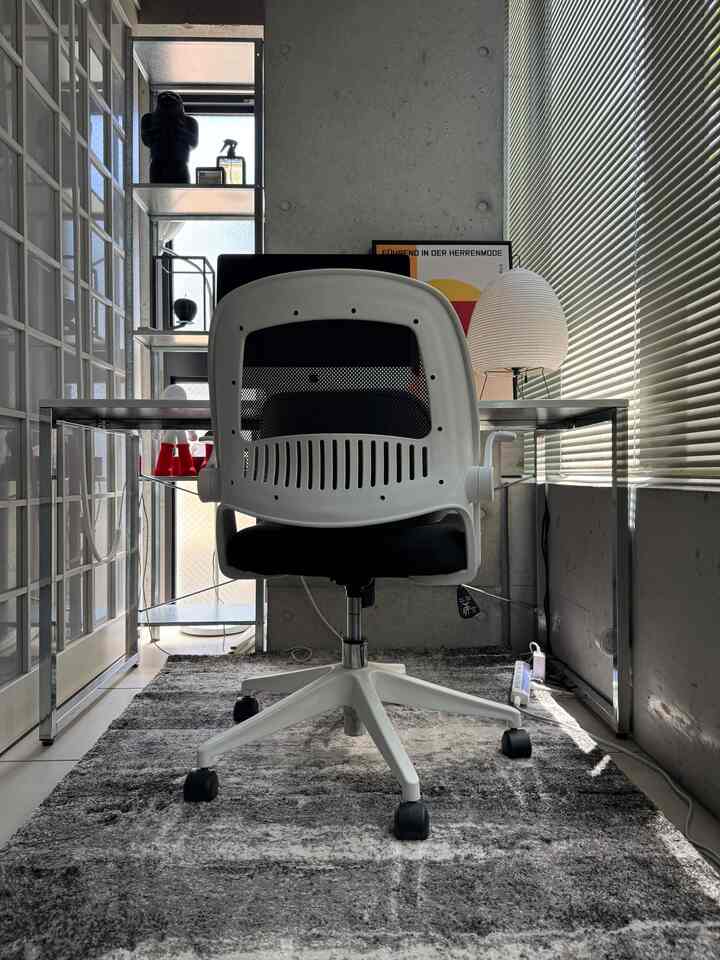 Monotone home office space featuring white office chair and glass desk with a clean, minimalist work setting