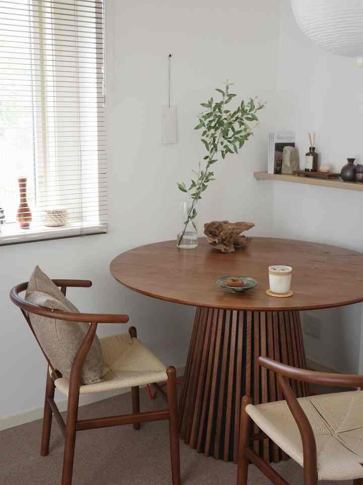 ブラウン色調のダイニング、丸いダイニングテーブルと椅子、テーブルの上に花瓶と飲み物が置かれた雰囲気のある和モダンな空間