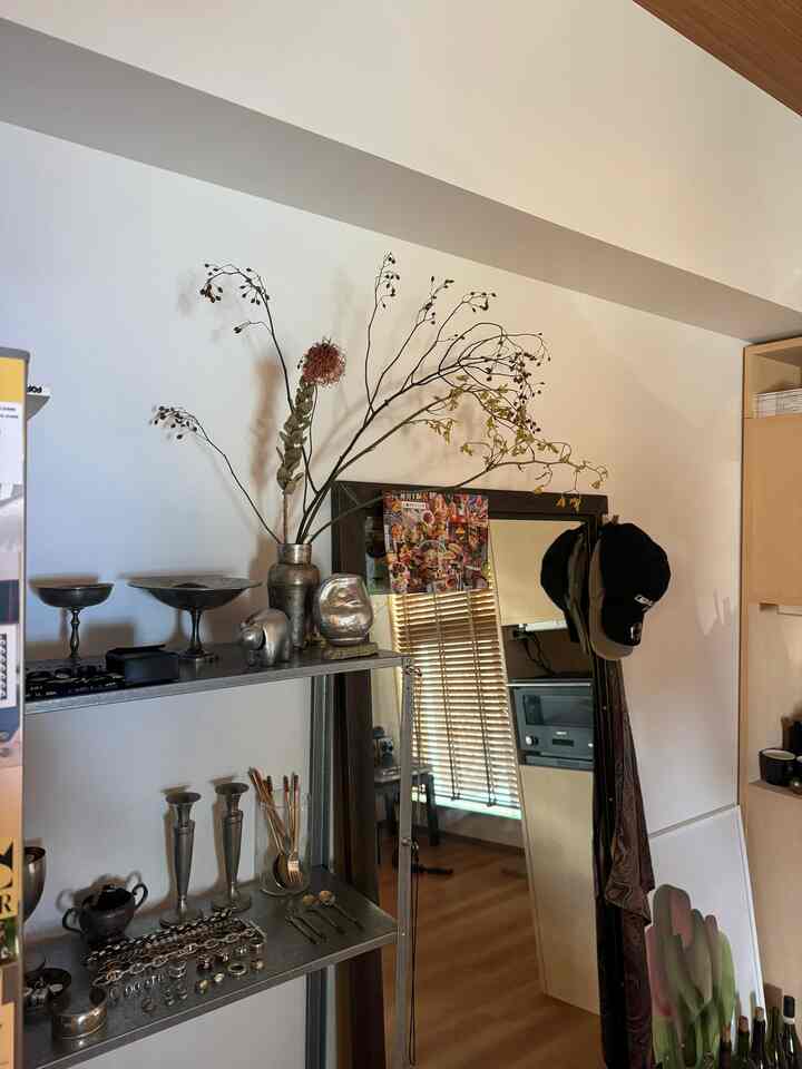 Natural tones in a single household space with white walls and brown floors, featuring a large black-framed mirror and metal shelving for an cozy atmosphere