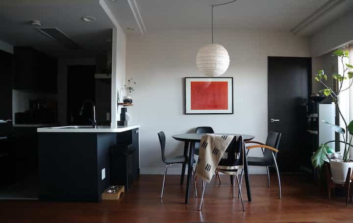 白と黒のトーンでまとめられたダイニングキッチンスペース、円形のダイニングテーブルと椅子が配置され、中に丸いペンダントライトがある洗練されたミッドセンチュリーモダンのインテリア